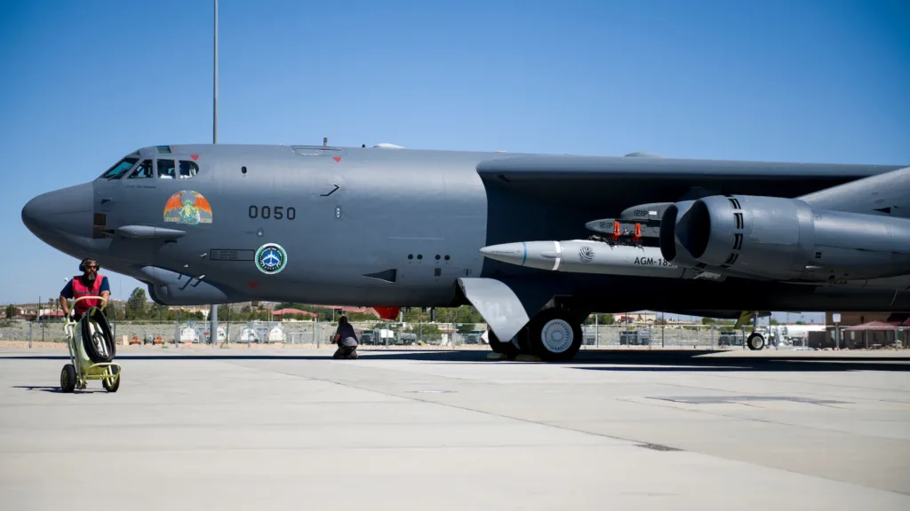 B-52 bomber with AGM-183 missile on tarmac, ground crew prepares for launch.
