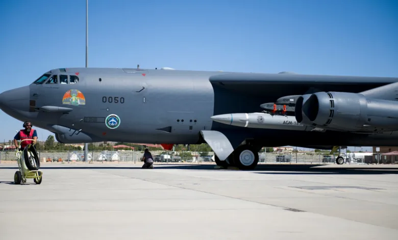 B-52 bomber with AGM-183 missile on tarmac, ground crew prepares for launch.