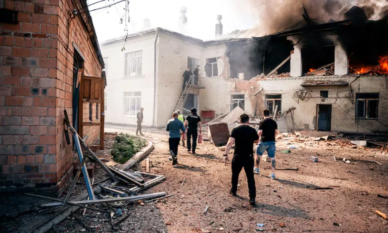 People in uniform run towards a burning building with smoke billowing from the roof.
