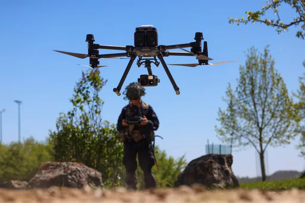 Drone operator controlling a DJI Matrice 300 RTK drone outdoors.