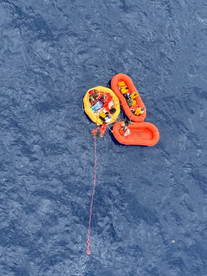 Three orange life rafts with survivors in the ocean
