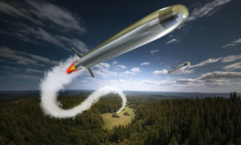 Two missiles fly over a forest, one leaving a smoke trail towards military vehicles below.