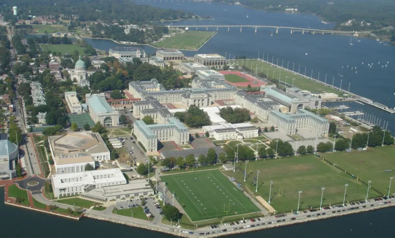 Aerial view of U.S. Naval Academy campus with buildings, sports fields, and water